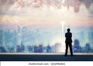 Vision concept. Successful businessman standing with hands crossed on chest, On top of building and looking through Cityscape Skyline Night Light.