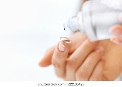 Vision Correction And Health Care. Woman Hands Pouring Solution From Bottle On Contact Eye Lens. Closeup With Bottle Of Eyelense Liquid. Ophthalmology And Optometry. High Resolution Image