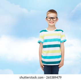 vision, education, childhood and school concept - smiling little boy in eyeglasses over blue sky with white clouds background