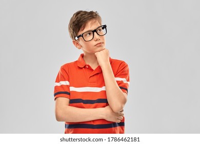 vision, education and school concept - portrait of thinking boy in eyeglasses and red polo t-shirt over grey background - Powered by Shutterstock