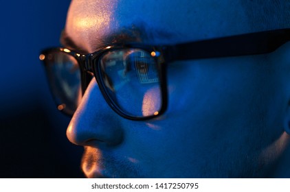 vision, hacking and technology concept - close up of hacker eyes in glasses looking at computer screen in darkness