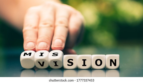 From a vision to a mission. Hand turns dice and changes the word vision to mission.