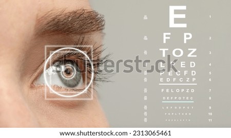 Vision test chart and laser reticle focused on woman's eye against light grey background, closeup