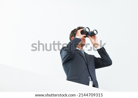 Visionary business man. Low angle view of handsome business man looking through binoculars.
