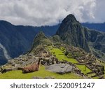 Visit Machu Picchu in the Andes near Cuzco. In the foreground is a llama, which makes the picture perfect. A few clouds and blue sky can be seen.