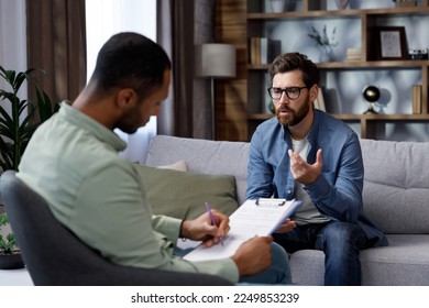 Visit to a psychologist. A man sits on a couch and talks to a psychotherapist. The patient is depressed, apathetic and stressed from problems in his personal life. Help of a psychologist.