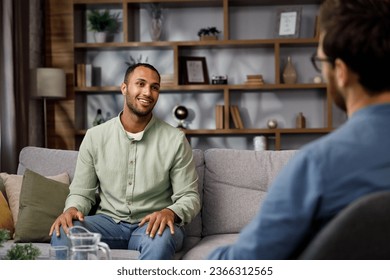 Visiting a psychologist A man sits on a couch and talks to a psychotherapist. He thanks the doctor and smiles, therapy helped him. Help of a psychologist.