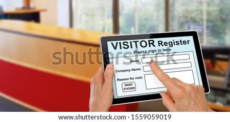 Visitor completing a sign in register form on computer tablet registration technology concept