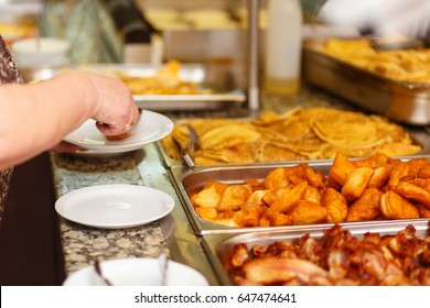 The visitor puts food in his plate at the buffet