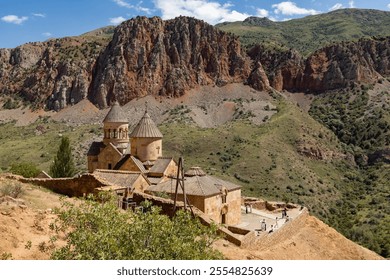 Visitors admire the ancient architecture of Noravank Monastery surrounded by stunning red rock formations. - Powered by Shutterstock