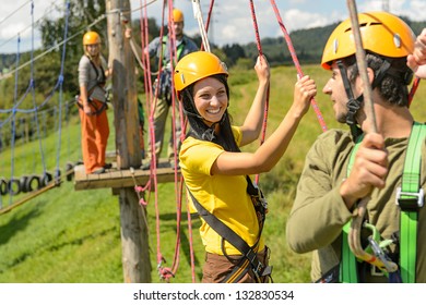 Visitors in adventure park clambering with ropes wear protective helmets - Powered by Shutterstock