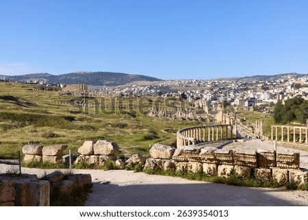 Visitors explore the ancient site of Jerash in Jordan, admiring well-preserved Roman ruins, columns, and the lush green landscape surrounding the historic city.
