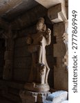 Visitors explore a cave temple filled with stone carvings. A statue stands out, showcasing the craftsmanship from years ago. The scene captures a moment of history in a sacred place.