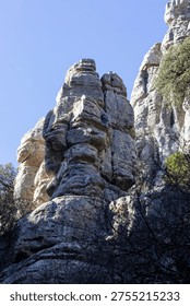 Visitors explore the unique rock formations in El Torcal, Spain. People walk through the area and admire the natural shapes and structures under the clear blue sky.