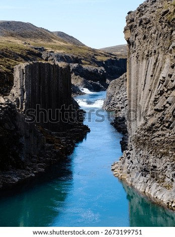 Visitors marvel at the striking basalt columns and turquoise river in Studlagil Canyon, Icelands stunning natural wonder, perfect for outdoor adventures and photography.