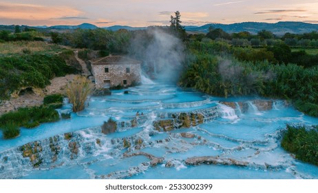 Visitors relax in Saturnia's soothing thermal waters, surrounded by lush landscapes and gentle waterfalls, creating a magical atmosphere of tranquility on a serene Tuscany Italy evening - Powered by Shutterstock