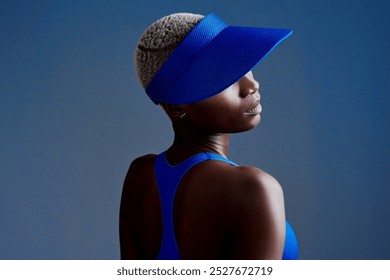 Visor, fashion and black woman in studio for tennis training, workout or match with athlete. Fitness, style and African female racket sport player with confidence for game practice by blue background - Powered by Shutterstock