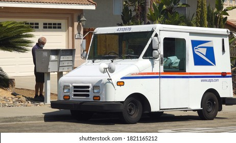 Vista, CA / USA - September 24, 2020: A US Postal Service Delivery Worker Brings Mail To A Mailbox In Suburban Neighborhood. He Is Wearing A Mask Due To Covid-19 Regulations.