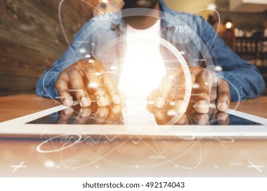 Visual effects. Dark-skinned man checking news feed and posting pictures on social networks, using high-speed Internet connection at coffee shop. Black man's hands touching screen of futuristic tablet - Powered by Shutterstock