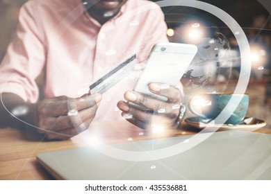 Visual effects. Worldwide connection interface. Cropped shot of African man, holding smart phone and credit card for making payments while shopping online, drinking cappuccino at a coffee shop