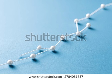 A visual metaphor for progress and interconnectedness, depicted by pearls strung together on a blue background.