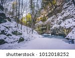 A visual of the sun lighting up the trees above overlooking the ravine and the frozen stream at Matthiessen State Park in Utica, Illinois.