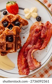 A visually appealing breakfast plate featuring crispy waffles, savory bacon, and fresh berries. Ideal for morning meal inspiration and culinary delight.