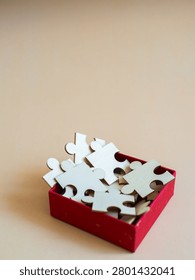 Visually appealing flat lay of unfinished puzzle pieces scattered in red box ideal for creativity and leisure themes.