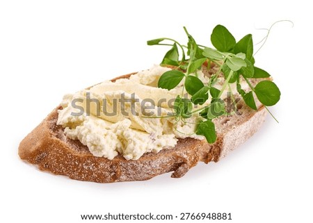 A visually appealing and nutritious open faced sandwich featuring dark brown artisan bread, a generous spread of light creamy cheese, and bright green pea tendrils, isolated on white background