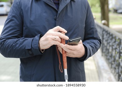 A Visually Impaired Man Holding A Cane And A Smartphone