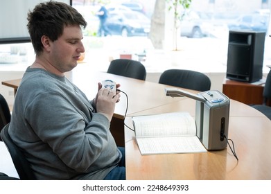 A visually impaired man uses a scanning and reading machine.