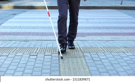 Visually impaired man using tactile tiles to navigate city, finishing crossroad