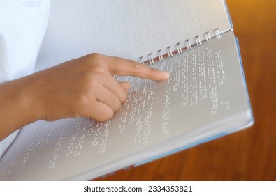 Visually impaired person reads with his fingers a book written in braille It is written for those who are visually impaired or blind. It is a special code generated from 6 dots in the box.            