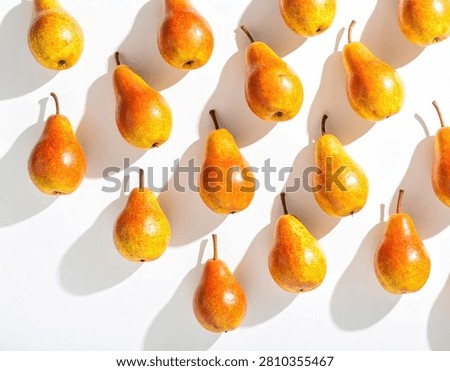 A visually striking pattern of fresh, ripe pears arranged diagonally on a clean white surface, casting distinct, elongated shadows.