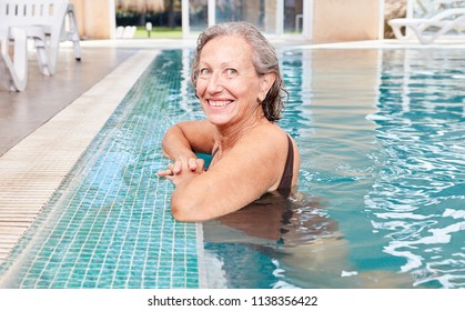 Vital senior woman at the poolside in a swimming pool or spa hotel - Powered by Shutterstock