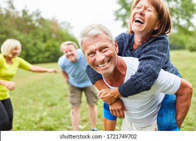 Vital seniors play together in the park in the summer and ride piggyback - Shutterstock ID 1721749702
