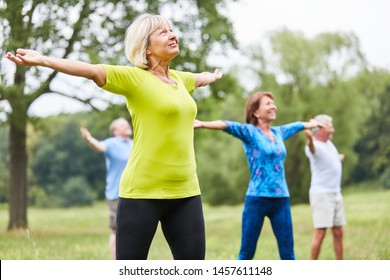 Vital seniors in a yoga or gym class with stretched arms