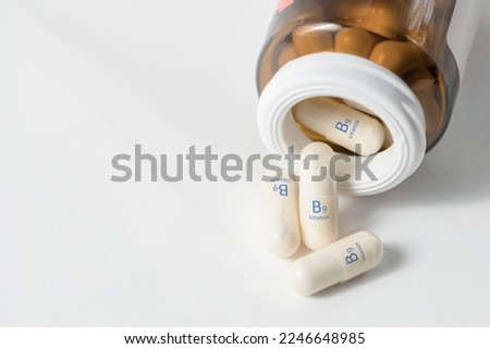 Vitamin B9. Capsules with folic acid, necessary for the growth and development of the circulatory and immune systems. White capsules of vitamin B9 or folic acid are scattered with copy space.