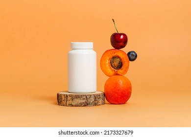 Vitamin Bottle Of Bio Supplement With Fresh Fruits On Wooden Stand. Mockup Medical Bottle, Multivitamin, Orange Background