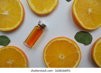 Vitamin C ampoule for injection with juicy 
slices of orange on a white table. A high dose of synthetic vitamin C for white skin. Mockup branding cosmetics. Healthy lifestyle. 