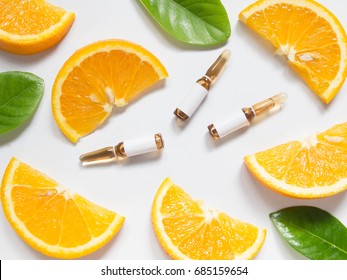 Vitamin C Brown Ampule For Injection With Fresh Juicy Orange Fruit Slices On White Table. High Dose Vitamin C Synthetic For White Skin. Beauty Product Branding Mock-up. Healthy Lifestyle. Top View.