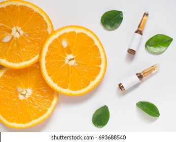 Vitamin C Brown Ampule For Injection With Fresh Juicy Orange Fruit Slices On White Table. High Dose Vitamin C Synthetic For White Skin. Beauty Product Branding Mock-up. Healthy Lifestyle. Top View.