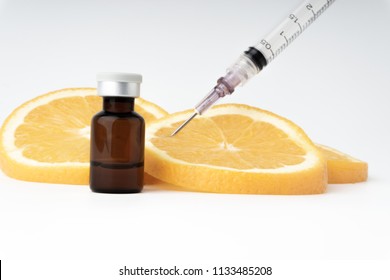Vitamin C brown ampule with syringe on fresh juicy orange fruit slides. Conceptual image  of mineral/vitamin/medical supplement and health. Selective focus and crop fragment