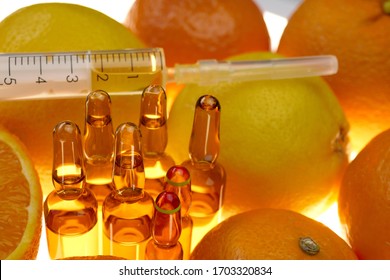 Vitamin C. glass ampoules set , syringe among the fruits of oranges and lemons on a white background.prevention of immunity from viruses.Serum with Vitamin C. Organic cosmetics concept. Health 