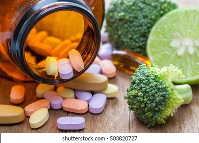 Vitamin C pills, broccoli and lemon on a wooden table, supplemental diet, healthcare and wellness concept