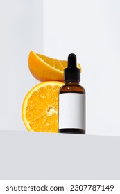 Vitamin C serum cosmetic bottle in  with oranges  on white background with copy space. Face care, beauty treatment, anti-aging, organic cosmetic industry concept. Cosmetics bottle mock up. 