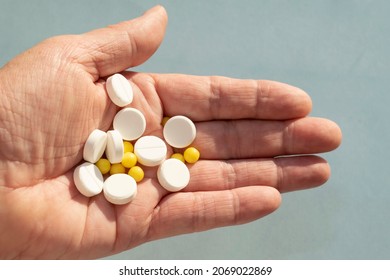 Vitamin C Tablets And Vitamin D Capsules In The Palm Of An Old Woman On A Blue Background. Vitamin For Health And Medical Concept, In The Treatment Of Coronavirus During The Covid-19 Epidemic