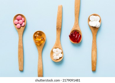 Vitamin capsules in a spoon on a colored background. Pills served as a healthy meal. Red soft gel vitamin supplement capsules on spoon. - Shutterstock ID 2179091481