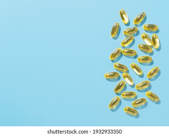 Vitamin D3, Omega or Evening Primrose Oil gel capsules on blue background. Top view or flat lay yellow liquid capsules with nutritional supplement oil. Copy space for text.