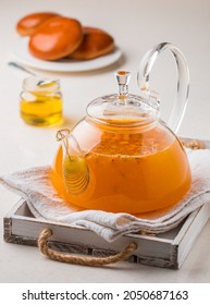 Vitamin hot sea buckthorn tea in a small glass teapot with fresh raw sea buckthorn berries and honey. Seasonal healthy drink. Selective focus - Shutterstock ID 2050687163